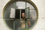 calcutta Man peers out of his window to watch the passing procession, Kailghat, Calcutta.