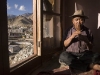 Man plays flute with view over Leh.