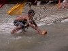 Kid picking offered coconuts out of the ganges to re-sell them to pilgrims