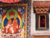 Monk watching Cham dance from a window next to a large thanka, Hemis Festival.